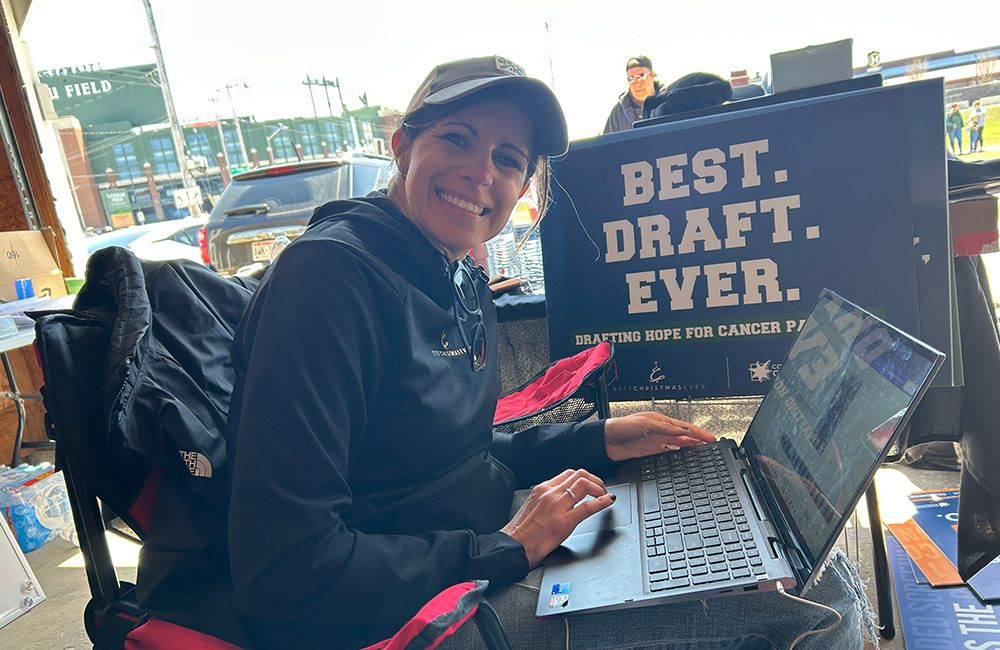 Kayla typing on a laptop in front of Best Draft Ever sign